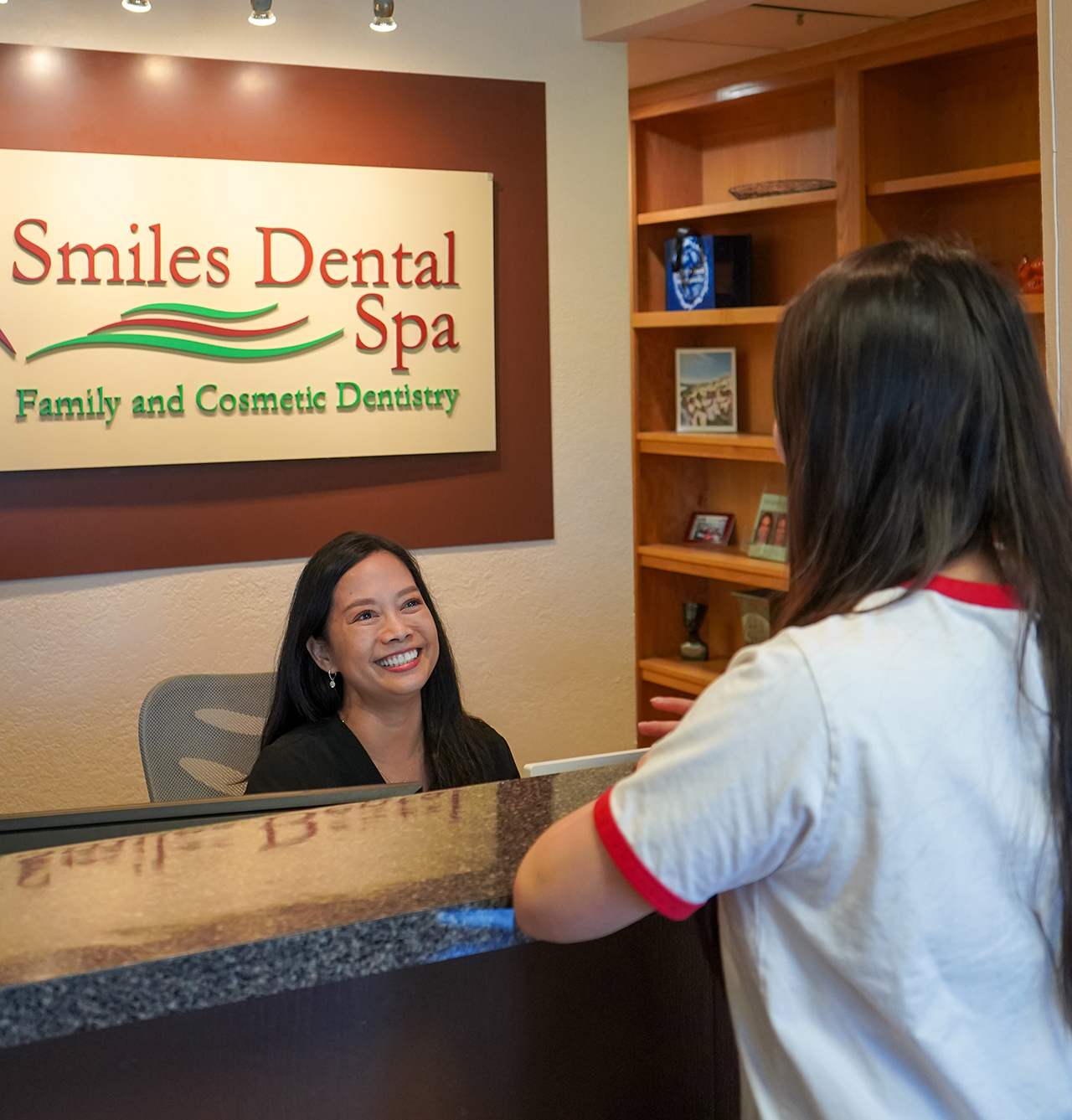 Christina, front desk staff at the dental office, assisting a patient with a warm smile.