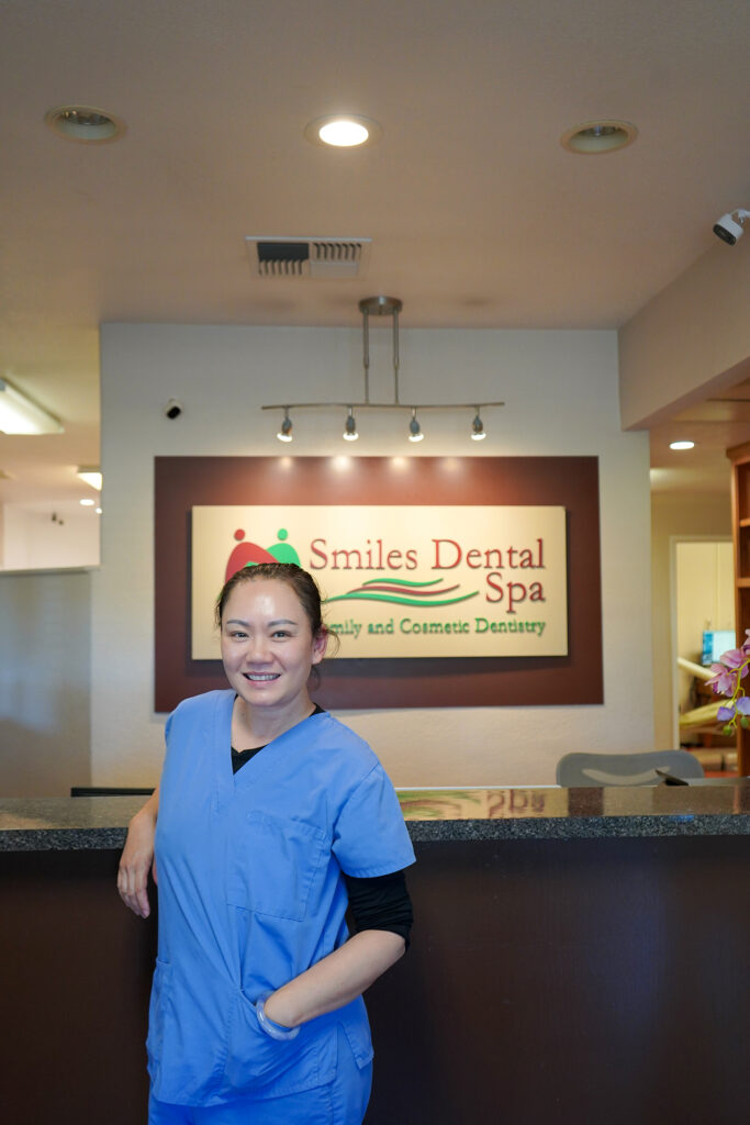 Dr. Shirley Zhao, DDS, standing in front of her dental office in Tracy, California, smiling and welcoming patients.